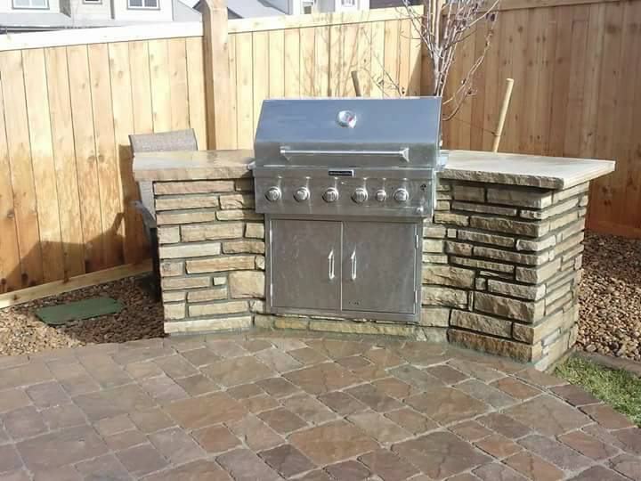 Grill on a brick patio in a backyard, showcasing a well-maintained outdoor space by a landscape company.