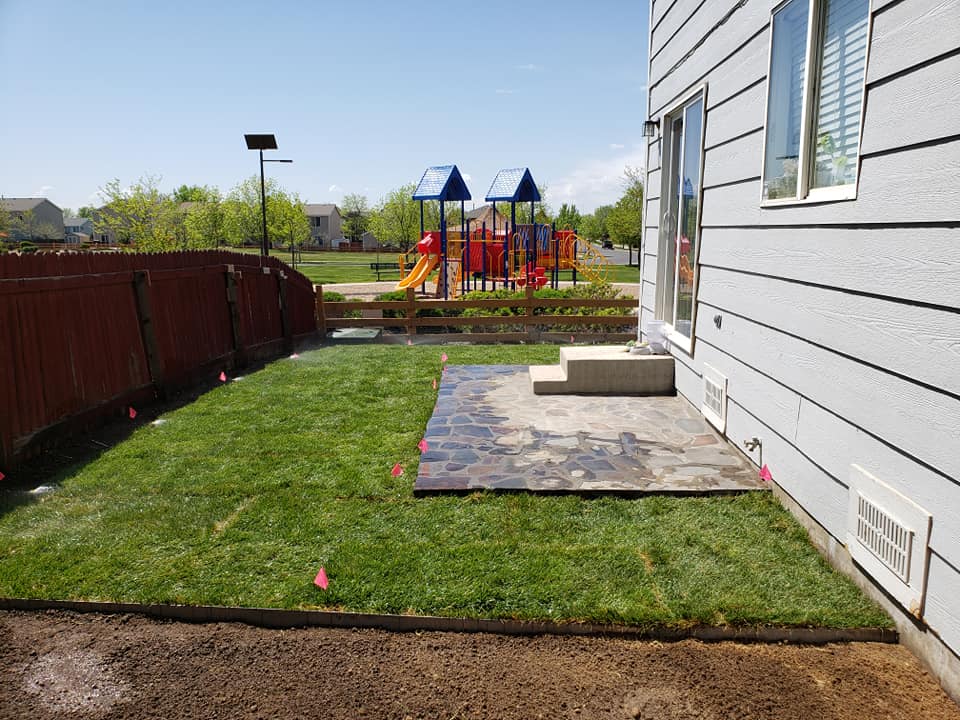 Backyard featuring a play area surrounded by a fence, designed by a landscape company for family enjoyment.
