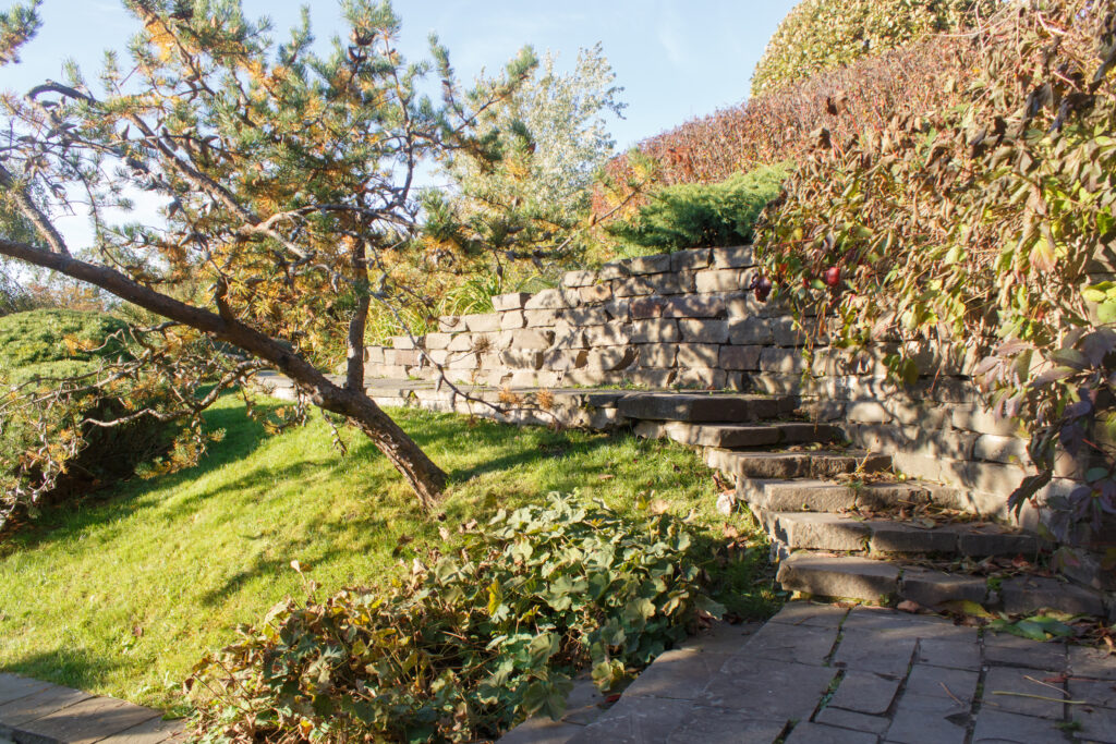 Retaining walls with built-in steps supporting a landscaped hillside and preventing soil erosion.