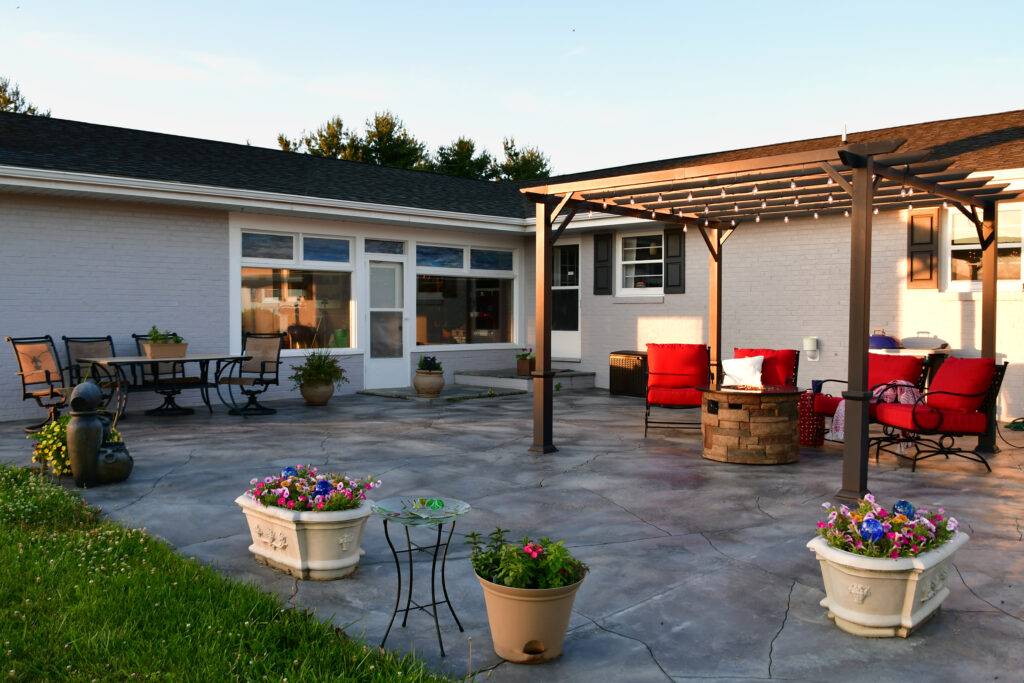 Stamped residential concrete patio with furniture and decorative planters.