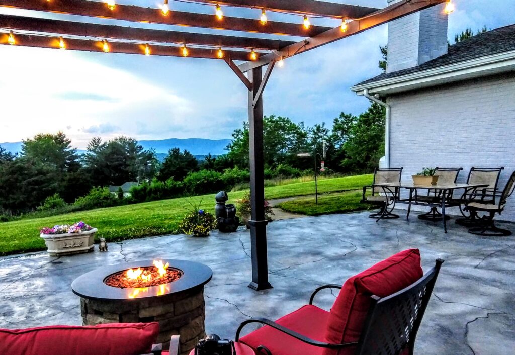 Showcasing a rustic stone design of custom patios with a fire pit and pergola.